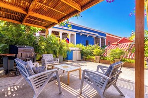 Un patio exterior con una parrilla, una zona de estar y vistas a un edificio azul con una bandera.