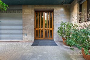 Un ingresso con porta in legno, persiana metallica e piante in vaso.