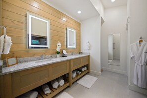 Ein modernes Badezimmer mit Holzvertäfelung, einem großen Spiegel und einem integrierten Handtuchhalter.