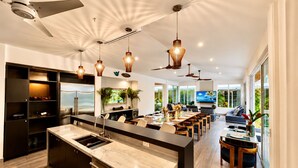 Une cuisine moderne dotée d’un plan de travail en marbre, d’appareils électroménagers intégrés et de luminaires suspendus.