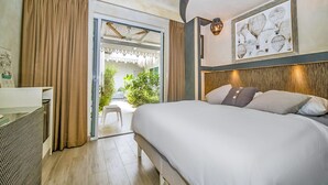 Une chambre d’hôtel moderne avec un grand lit, un bureau et une vue sur la verdure par la fenêtre.