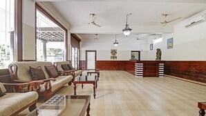A spacious lobby with a reception desk, multiple seating areas, and ceiling fans. - Treebo Trend Green Palm Resorts (Neyyattinkara)