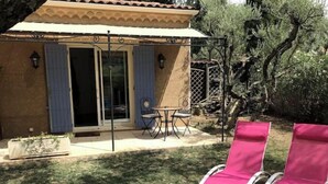 A patio with two pink lounge chairs, a table, and a chair.