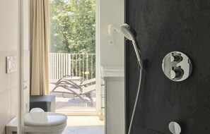 A bathroom with a shower, toilet, and a balcony with outdoor furniture. - Dünenvilla Penthouse Superior (Lübeck)