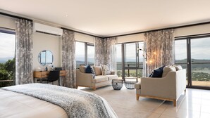 Une chambre moderne avec un grand lit, un bureau, deux canapés et une vue sur l’extérieur.