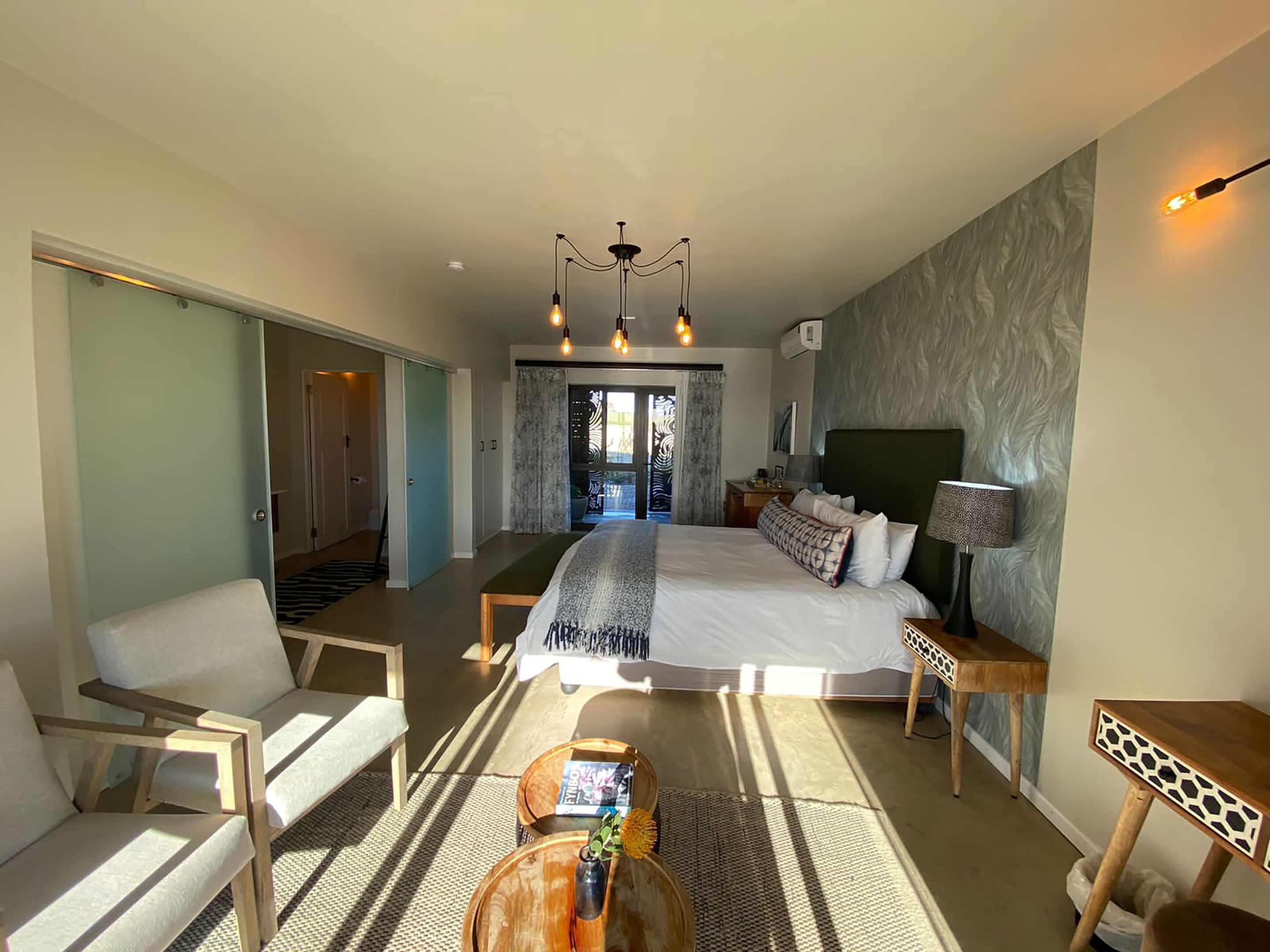 Een moderne hotelkamer met een groot bed, een zithoek met een salontafel en uitzicht op de omgeving.