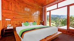 Un dormitorio con paneles de madera, una cama, una mesita de noche y un ventanal que ofrece vistas al exterior.