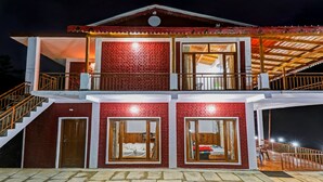 Un edificio de dos pisos con fachada de ladrillo rojo, ventanas grandes y una escalera de madera.