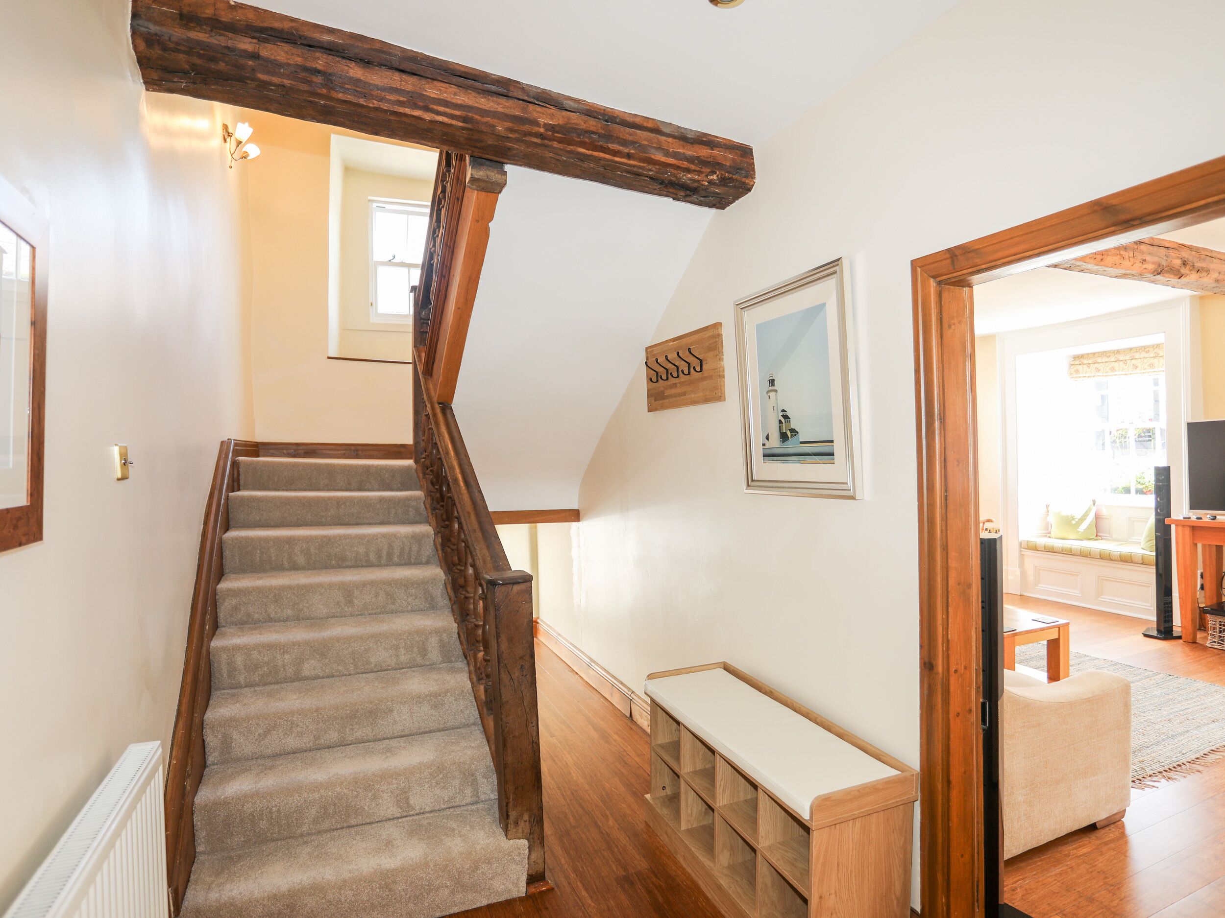 A staircase with wooden railings, a bench, and a framed picture of a lighthouse.