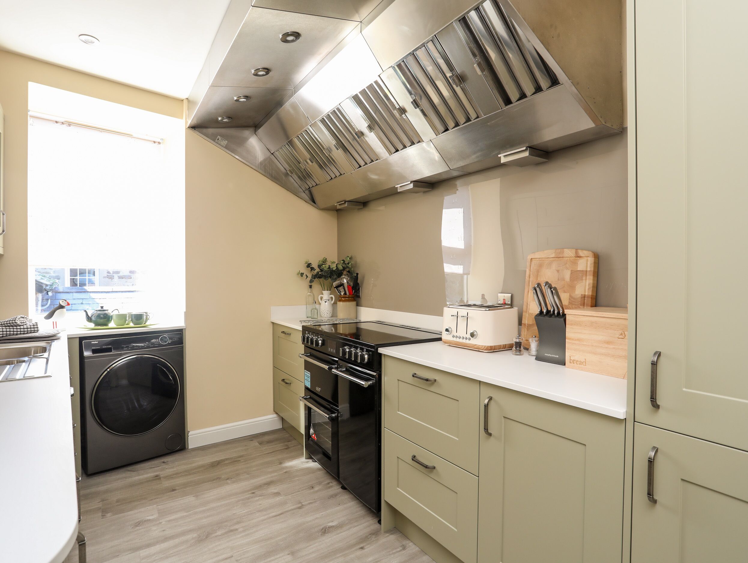 A compact kitchen with a built-in washer, a stove, and a toaster.