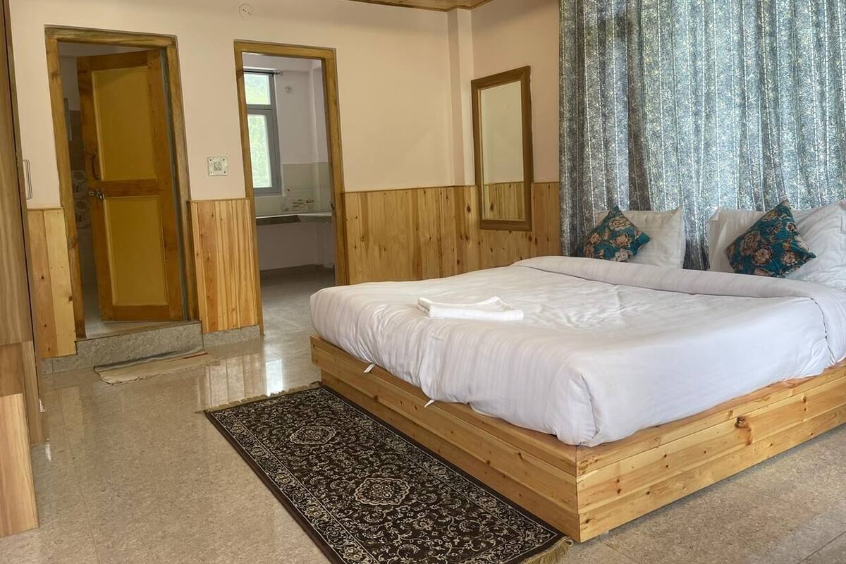 Un dormitorio con estructura de cama de madera, un espejo grande y un tapete estampado.