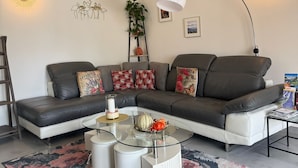 Una sala de estar moderna con un sofá modular, una mesa de centro de vidrio y detalles decorativos en la pared.