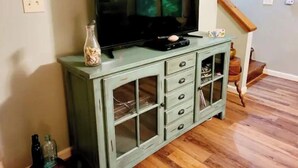 A living room with a television on a cabinet, wooden flooring, and a staircase. - Spacious suite surrounded by nature with living room, fireplace, porch, fire pit (Blowing Rock)