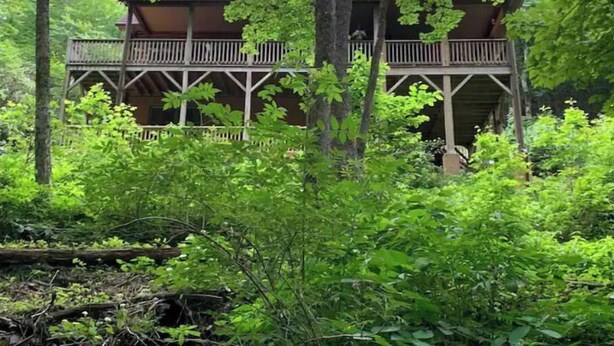 A wooden cabin with a balcony, surrounded by dense forest. - Spacious suite surrounded by nature with living room, fireplace, porch, fire pit (Blowing Rock)