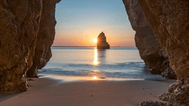 Une plage avec une formation rocheuse au centre, encadrée par des arches naturelles.