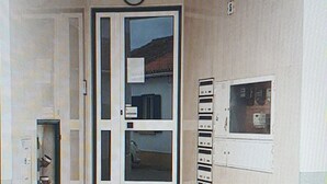 Une entrée moderne avec une porte en verre, une petite vitrine sur la gauche et un panneau de sécurité sur la droite.