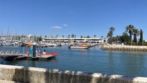 Un port de plaisance avec des bateaux amarrés, un bâtiment portant l’enseigne « MAMMA DELACOE » et des palmiers.