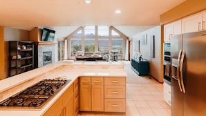 A kitchen with a central island, a stove, a refrigerator, and a dining area with a view of the mountains. - Beautiful 30+ Stay | Amazing Views | Large Deck | Air Conditioning (Ridgway)