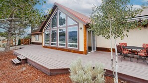 A modern house with a large deck, a dining area with outdoor furniture, and a view of the surrounding landscape. - Beautiful 30+ Stay | Amazing Views | Large Deck | Air Conditioning (Ridgway)