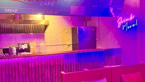 A lounge area with a neon sign reading "Drink More," a counter with a menu, and a seating area with cushions. - Slumber Party Krabi  (Krabi)