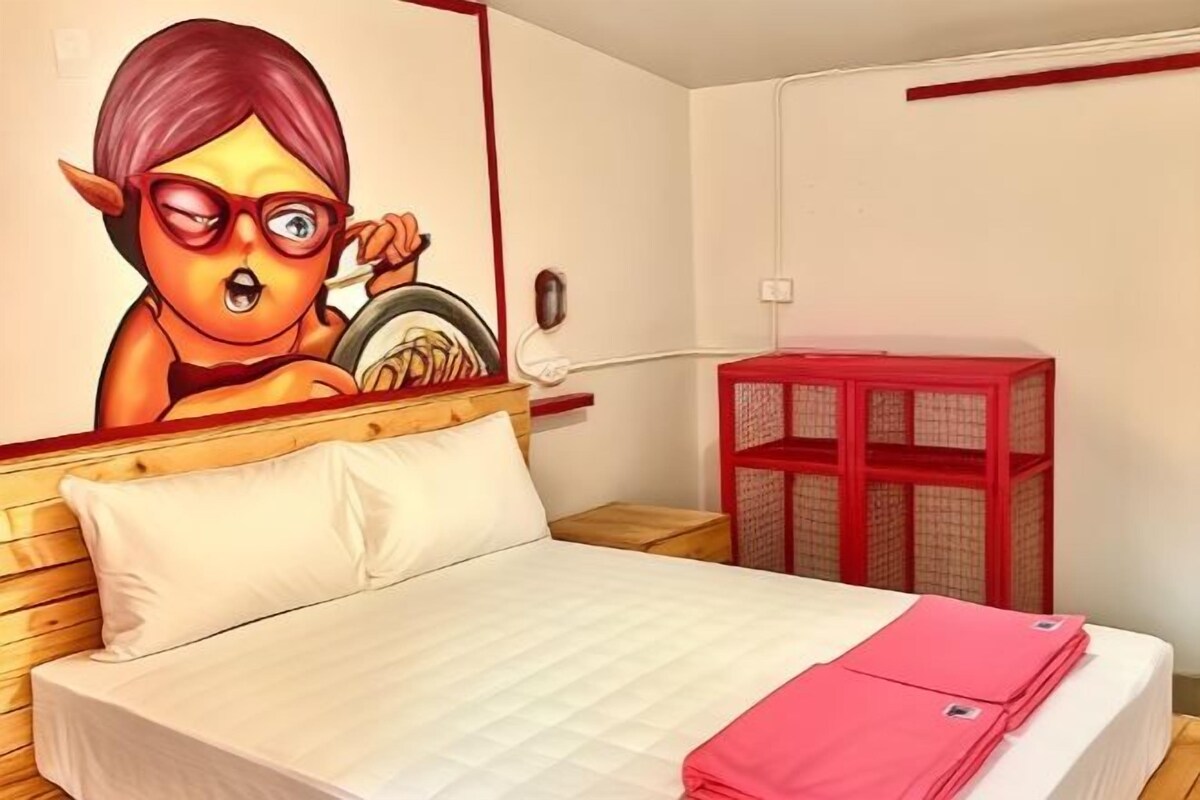 Quarto com uma cama, um móvel de armazenamento vermelho e uma parede com um personagem de desenho animado.