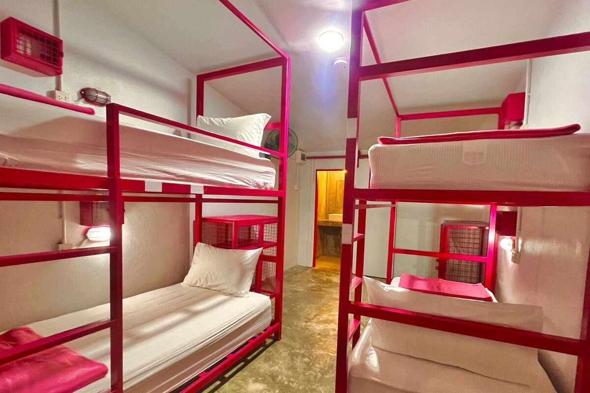 Une chambre avec deux lits superposés, chacun étant équipé d’un matelas et d’un oreiller. La chambre contient également une petite table et une chaise.