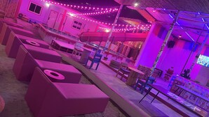 A beachside lounge area with seating and a stage, decorated with string lights. - Slumber Party Krabi  (Krabi)