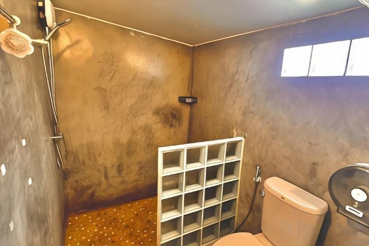 A bathroom with a shower, toilet, and a shelf unit.