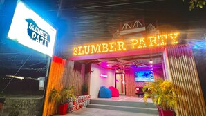 A building entrance with a neon sign reading "SLUMBER PARTY" and a sign above the door. - Slumber Party Krabi  (Krabi)