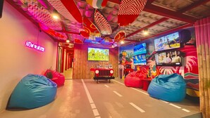 A vibrant room with a neon sign, bean bags, a TV, and a gaming area. - Slumber Party Krabi  (Krabi)