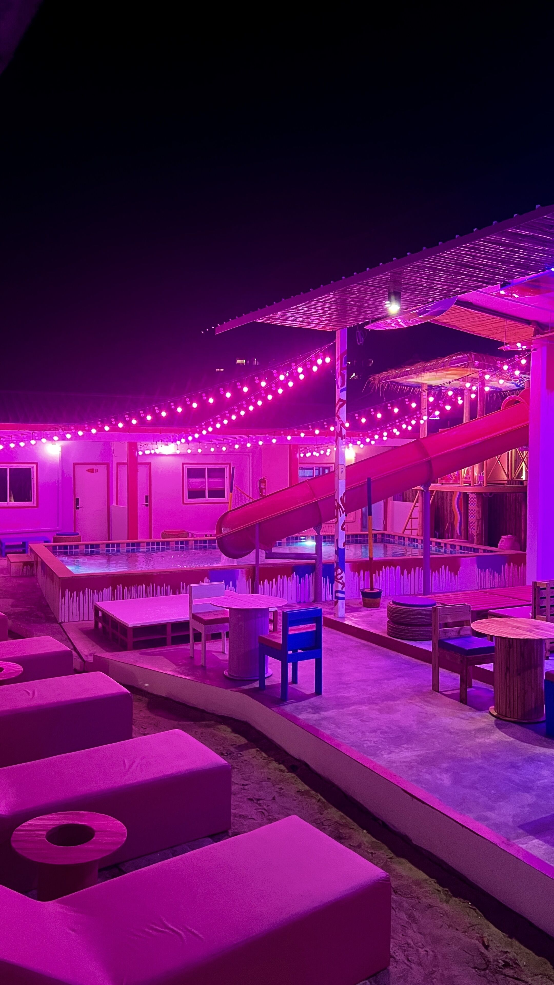 A building with a covered outdoor area, a slide, and seating arrangements.