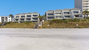 Un hotel frente a la playa con varios balcones y una escalera que baja a la arena.