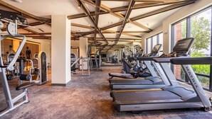 Et fitnesscenter med løbebånd, styrkemaskiner og et spejl.
