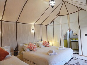 A tent-style room with two beds, a nightstand, and a hanging lantern. - Luxury tented camp in the desert of Merzouga (Merzouga)