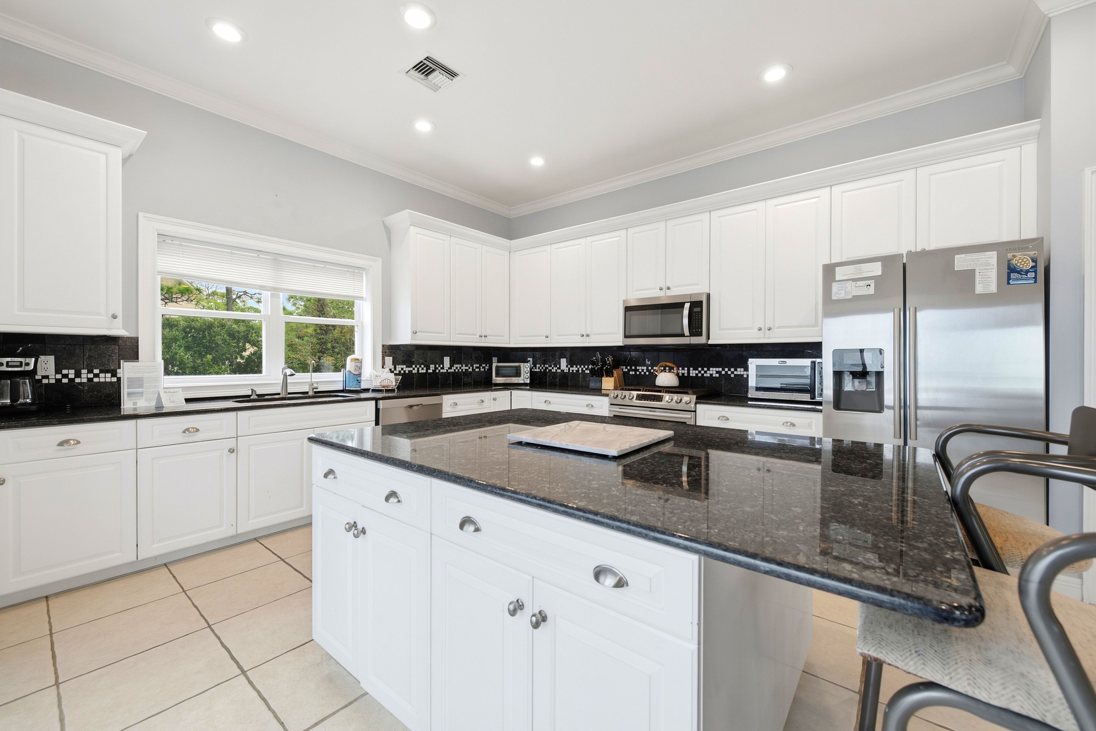 A modern kitchen with white cabinetry, a granite countertop, and stainless steel appliances.