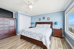 A bedroom with a bed, nightstands, a dresser, and a ceiling fan.