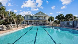 A swimming pool with clear blue water, surrounded by palm trees and a large building with a balcony. - Welcome to La Vista! (St. George Island)