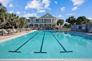 A swimming pool with clear blue water, surrounded by palm trees and a large building with a balcony. - Welcome to La Vista! (St. George Island)