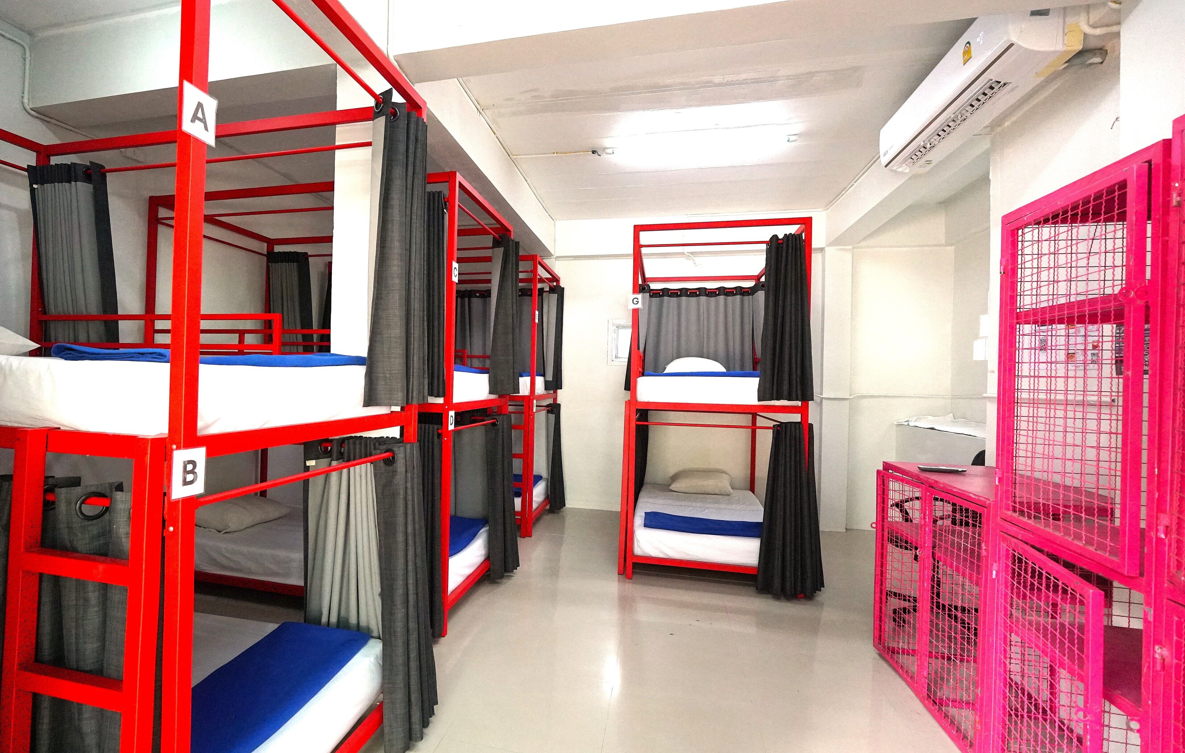 Um dormitório com beliches, cortinas e uma gaiola rosa.