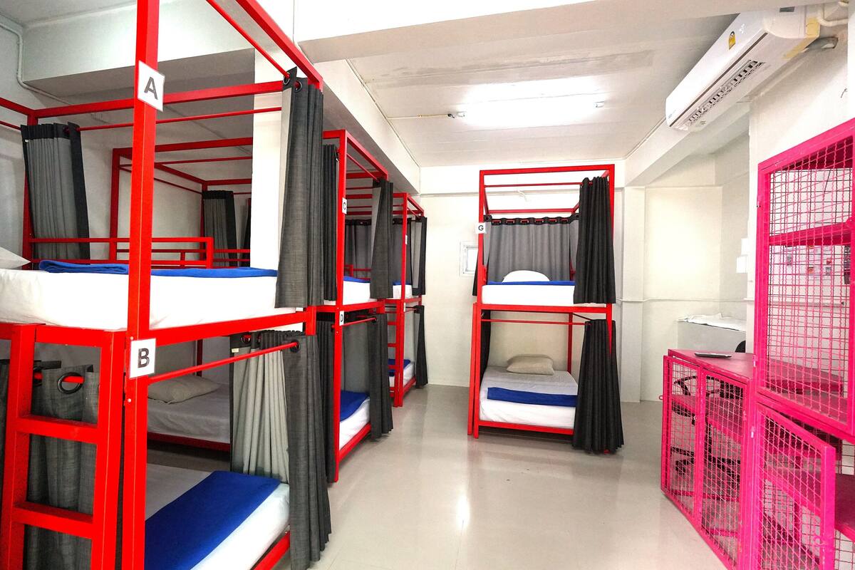 A dormitory with bunk beds, curtains, and a pink cage.