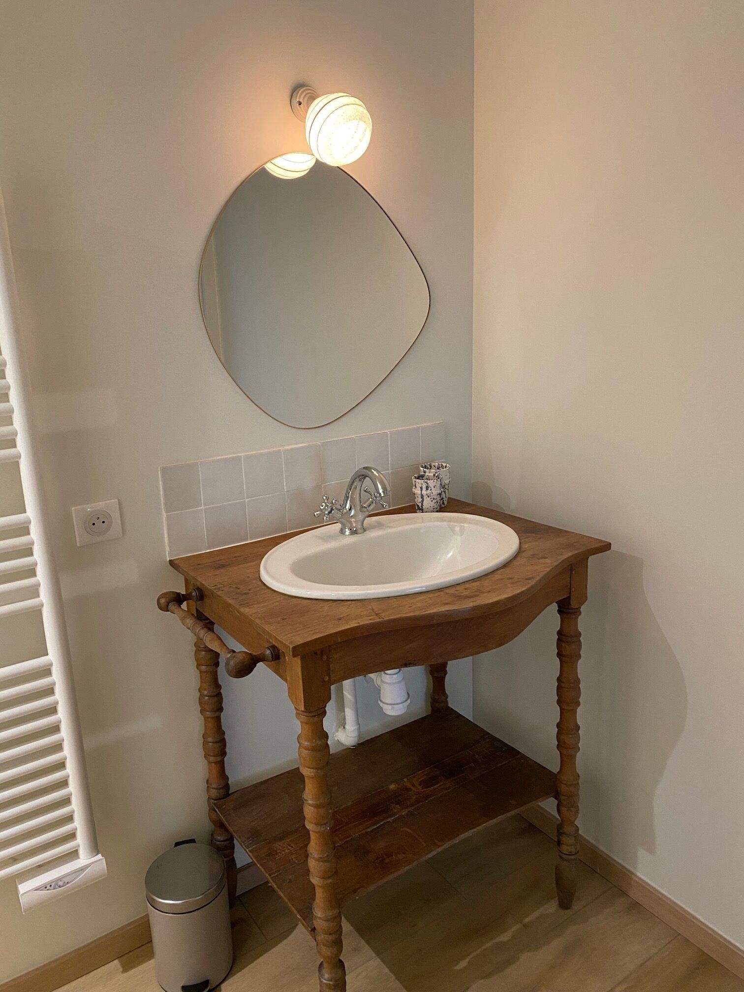 A bathroom with a wooden vanity, a white sink, and a mirror.