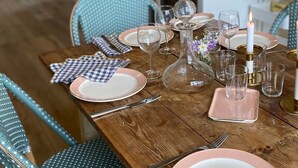 A dining table set with plates, glasses, and cutlery, with a candle and decorative flowers.