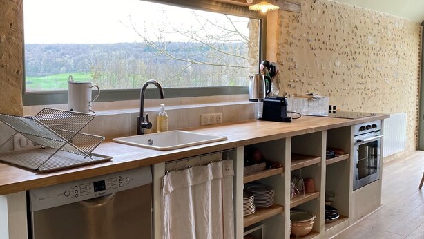 A modern kitchen with a large window, wooden beams, and built-in appliances.