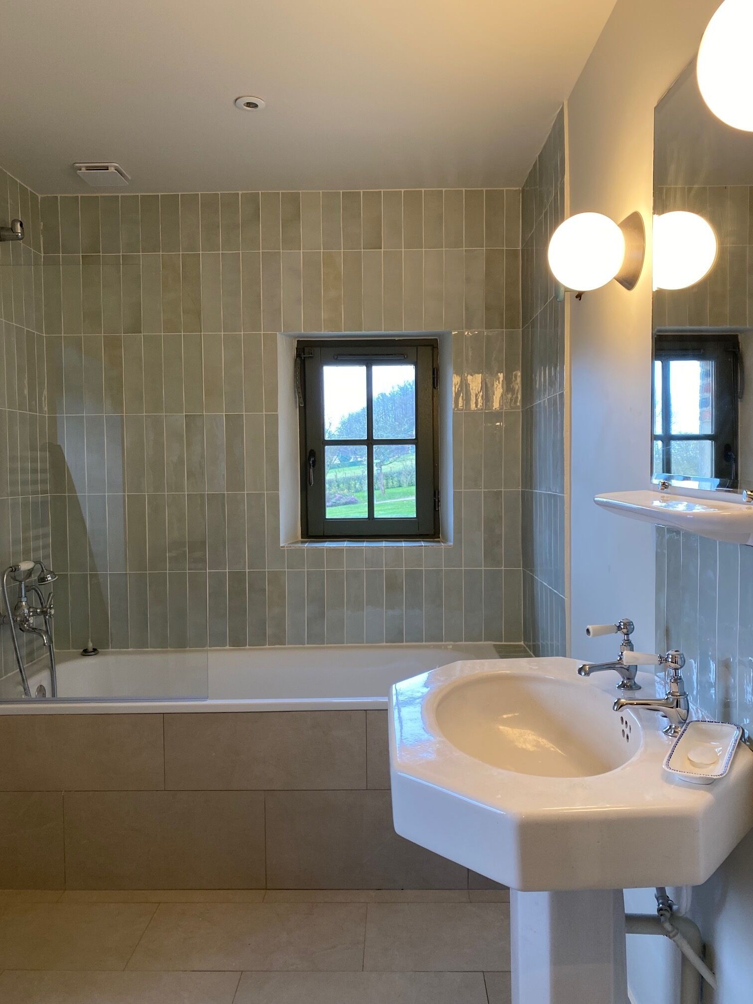 A modern bathroom with a bathtub, a sink, and a window with a view of greenery.