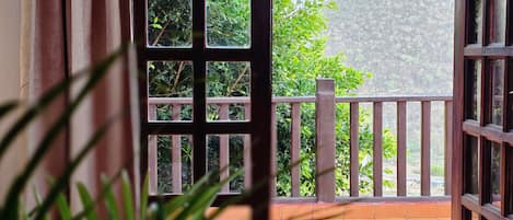 An open door leading to a balcony with a view of a hillside.