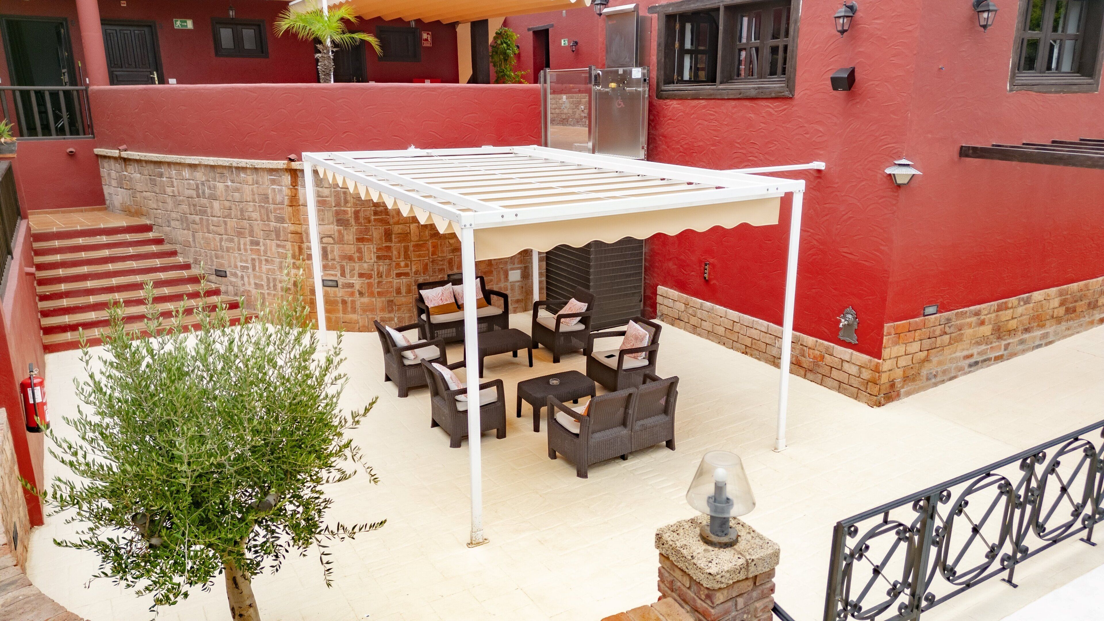 Une terrasse extérieure avec des meubles en osier, un espace salon couvert et un mur en pierre.