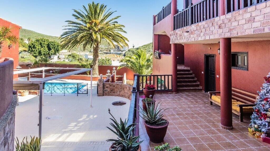 A courtyard with a pool, potted plants, a staircase, and a Christmas tree.