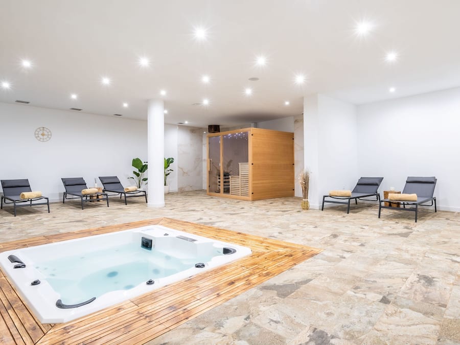 A spa area with a hot tub, lounge chairs, and a wooden sauna.