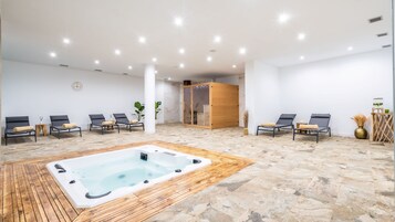 Un área de spa con hidromasaje, sillones reclinables y una sauna de madera.