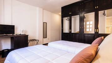 A bedroom with a large bed, a TV, a wardrobe, and a desk.